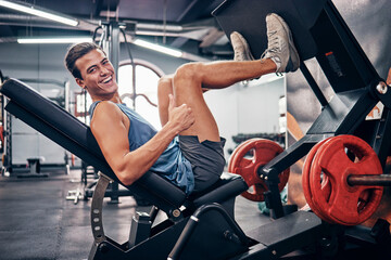 Gym, thumbs up and leg press in gym, smile and happy for fitness development, success and good workout. Portrait of male training, motivation and wellness with hand gesture for like, emoji and yes