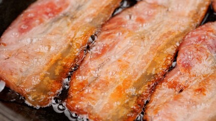 Bacon. Frying bacon in pan, close up. Traditional breakfast