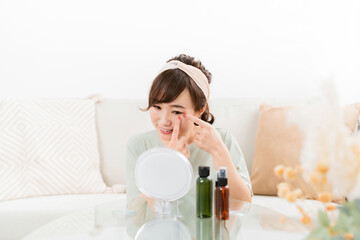 Fototapeta na wymiar 鏡の前で目を見る笑顔の日本人女性（コンタクトレンズ） 