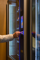 Woman's hand putting a bitcoin coin in a vending machine to buy a snack. Concept of sale, technology and consumption