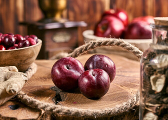 Red plums on an old wooden table top.