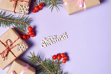 Christmas gift boxes with fir branches and rowan berries on purple paper background with copy space