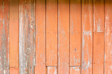 The orange wooden wall with some peeling paint due to aging.