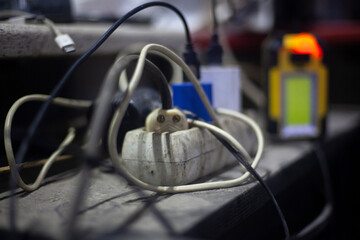 The charger is plugged in. Entangled wires from sockets of various devices. Chaos in home wired...