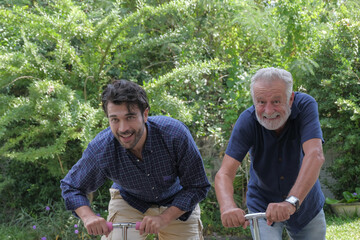 Fototapeta premium Happy old father and his son are playing scooters cheerfully together at outdoor garden house on holiday.