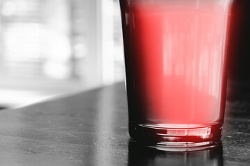 A glass with a red cocktail on monochrome gray background, closeup, crop, space for text