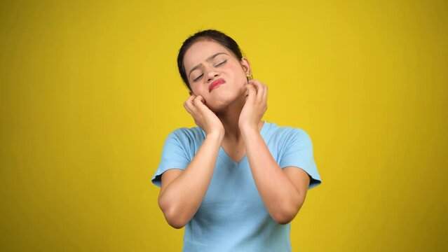 Young woman scratching face or cheek, isolated over yellow background. Annoying itching and rashes due to allergic reaction