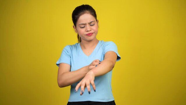 Young women have skin problems, irritation on her skin, skin infection itching red rash, arm scratching with hands, isolated over yellow background