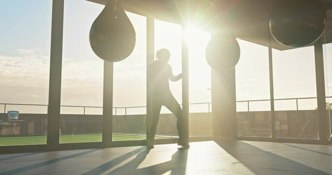 Fitness, kick boxing and woman training with a punching bag for strength, exercise and sports in a gym. Martial arts, motivation and female athlete practicing for a MMA fight with a workout in a dojo