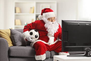 Santa claus sitting on a sofa and watching football