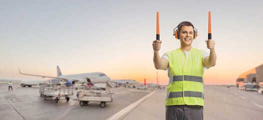 Aircraft marshaller signaling with wands at an airport apron