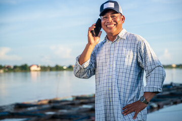 Tilapia Aquaculture farmer Businessmen use their mobile phones to contact their partners or agree to sell their produce.