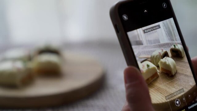 Close up of woman holds smartphone taking pictures of sweet dessert cheesecake.