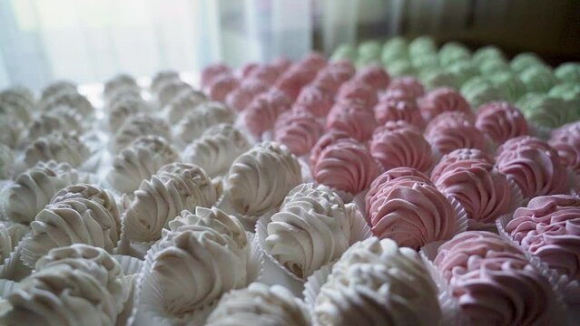 Many red, green and white cooked marshmallows lie on the table. Camera rotating