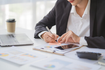 Portrait of beautiful smiling young entrepreneur businesswoman holding cup of coffee and working on laptop computer at office. Panoramic background.