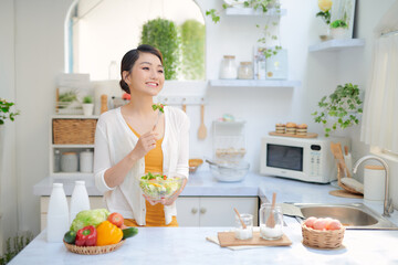 Obraz na płótnie Canvas .Young woman eating fresh salad in modern kitchen.