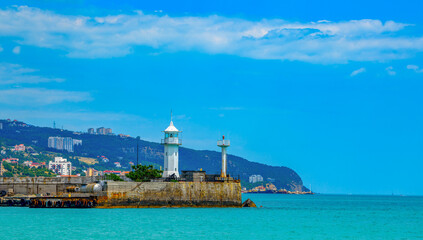 Yalta lighthouse in Crimea on the Black Sea at the passenger seaport on the background of beautiful clouds.