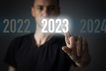Finger pressing blue start 2023 button on virtual interface on gray background with copy space for text. Concept of new year. Businessman pressing 2023 start up business. Beginning of New Year 2023.