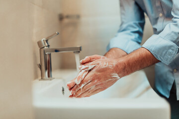Man using soap and washing hands under the water tap. Hygiene concept hand closeup detail. 