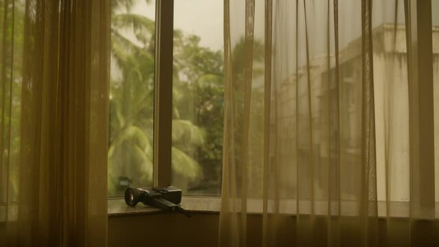 Canon Super 8mm Camera on Window Sill warm room, golden heat, india, palm trees in background, warm sheers and curtains camera photography and travel video capturing memories on holiday