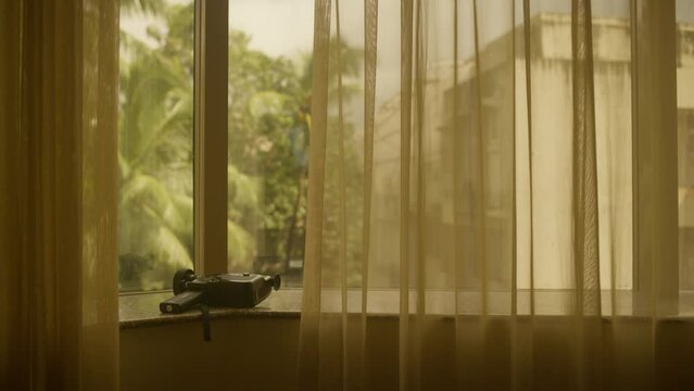 Canon Super 8mm Camera on Window Sill warm room, golden heat, india, palm trees in background, warm sheers and curtains camera photography and travel video capturing memories on holiday