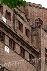 Teilaufnahme Blick auf Fenster eines Gefängnisses hinter Stacheldrahtzaun, vertikal 