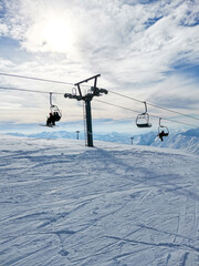 Ski resort. People on ski lift. Snow-capped mountains sunny day. Active winter sport. Ski slope with ski lift and people