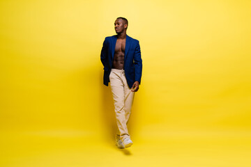 Fototapeta na wymiar Guy in blue suit on yellow background. Handsome athletic man in jacket smiling