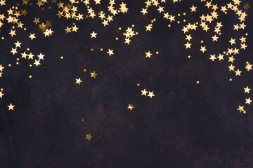 Golden stars on abstract dark holiday background with copy space