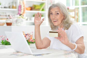 Senior woman using laptop at home shopping online