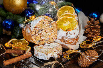 Christmas stollen with spices, raisins, nuts and candied fruits on a background of glowing garlands