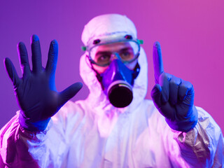 Coronavirus covid-19 pandemic. Doctor scientist wearing protective biological suit and mask due to global healthcare epidemic warning and danger background in blue and pink neon lights background.
