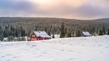 Wintertime landscape of Jizera Mountains. Snowy meadows and old wooden house on cold winter day. Jizerka, Czech Republic.
