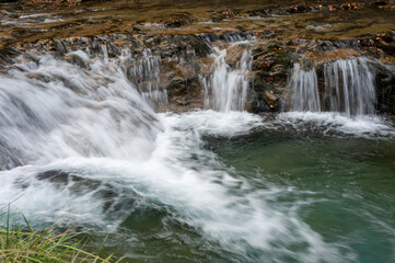 A waterfall in an autumn valley. Golden leaves and silky waters