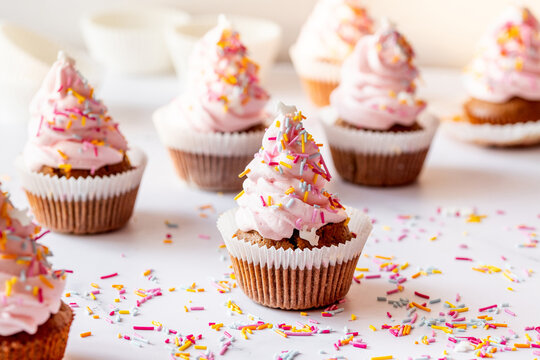 Frosted homemade carrot cupcakes with colorful birthday sprinkle close-up, horizontal image
