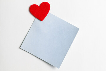 Close-up of a short blue note paper with a red heart. Valentines Day background. Copy for writing text. Concept of recognition of love, romantic relationships, Happy Valentine's day