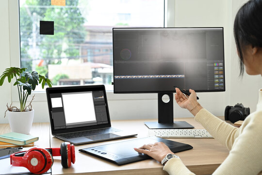 Over shoulder view of video editor editing video footage on personal computer at her workstation