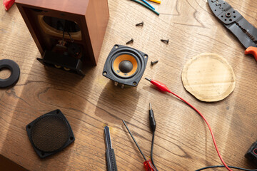 Speaker repair, speaker building, audio workbench scene. Disassembled speakers on an old wooden work desk with electronic equipment.     