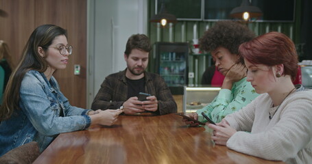 Group of students watching mobile phones at coffee shop. Young people addiction to new technology trends. Alienation moment for new generation problem