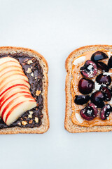 Various kind of open sandwiches with berries and fruits. Made from wholegrain bread and different nut butter, such as peanut butter and crunchy cashew or almond butter