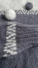 Fototapeta na wymiar Handmade sweater. Knitted fabric from mink thread. White and gray color pattern.