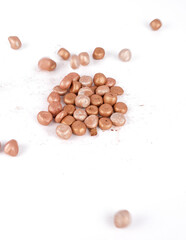 Balls of bronzing face powder falling on table, bronzing pearls isolated on white background