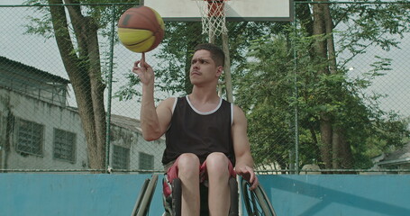 One disabled paraplegic athlete spinning ball outdoors sitting on wheelchair