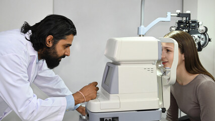 Indian male ophthalmologist examining eyes of a patient with digital microscope in the ophthalmologic office. Eye care concept