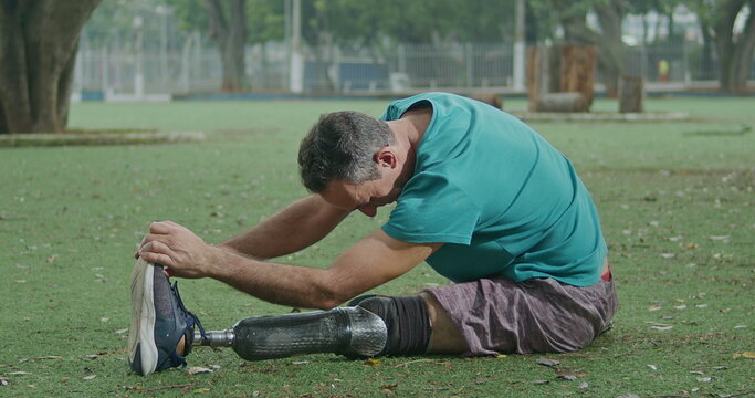 One motivated older middle aged disabled athlete stretching prosthetic leg - Powered by Adobe