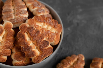 Tree shaped butter cookies close up in a bowl on a dark grey background. Copy space.