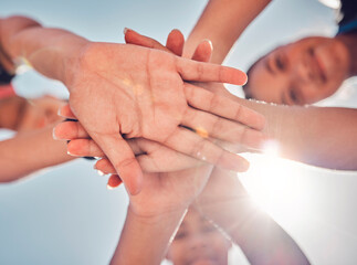 Hands, teamwork and collaboration of friends, community or people together for charity, support and motivation outdoor with lens flare. Group together for trust, commitment and synergy from below