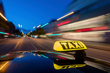 Illuminated taxi sign on moving car roof at night