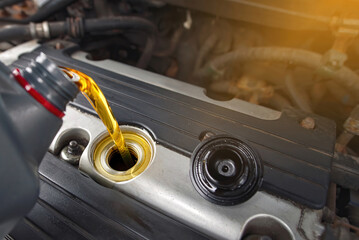 Pouring new motor oil into engine at car service station. Oil change. Filling up lubricants, motor...