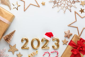 Fototapeta na wymiar New year 2023 number, golden digits and santa hat over blue background.